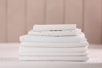 Photo of Stack of clean folded linens on bed indoors