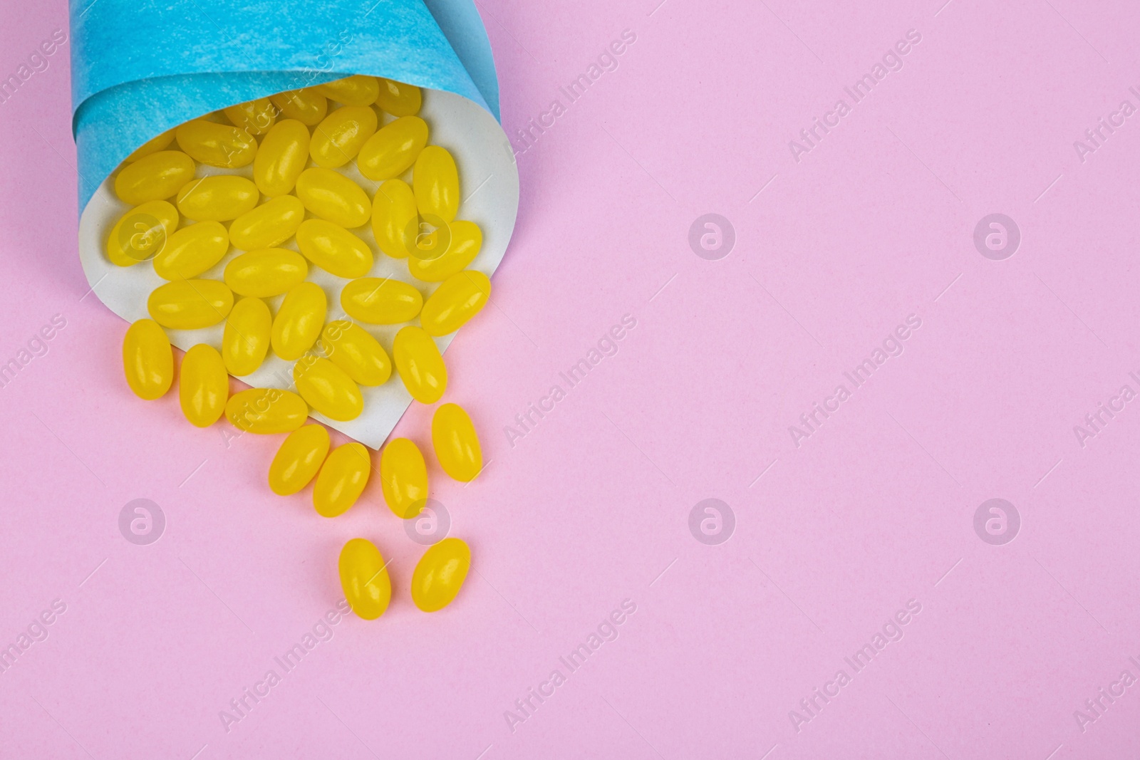 Photo of Delicious lemon jelly beans on pink background, top view. Space for text