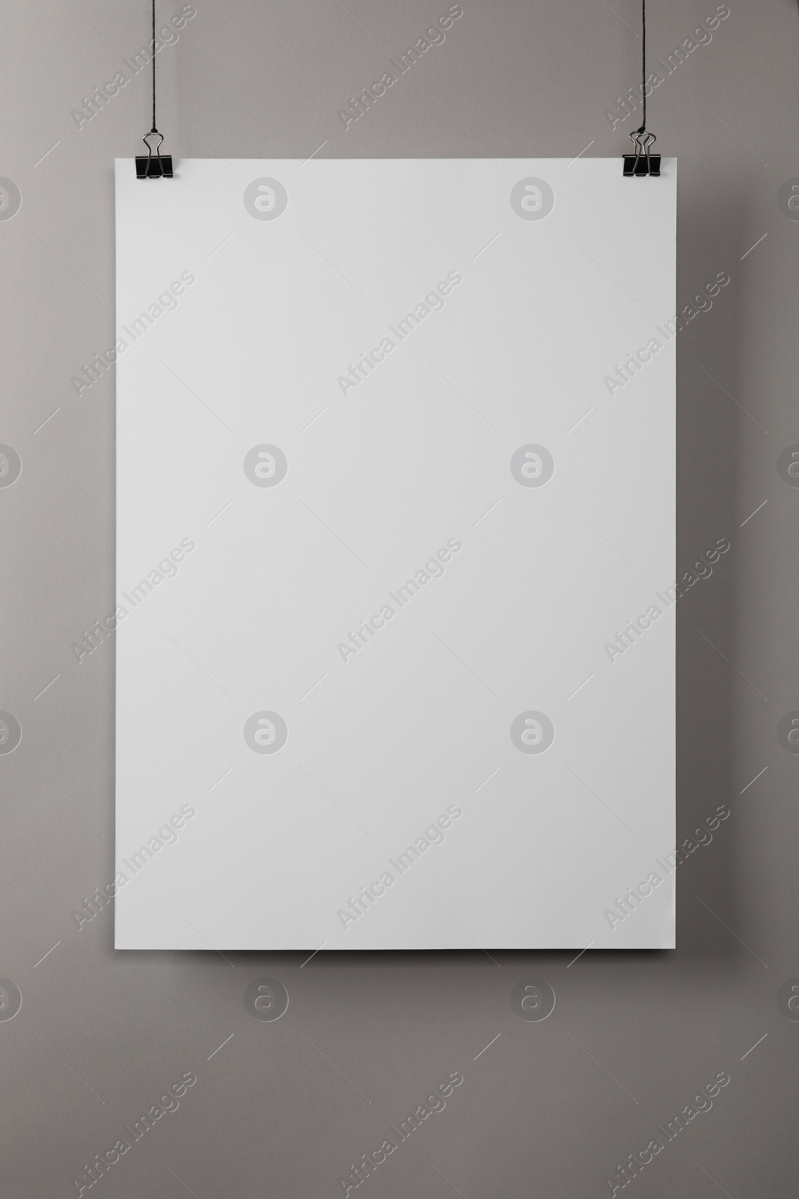 Photo of White blank poster hanging near grey wall