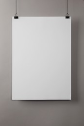 Photo of White blank poster hanging near grey wall