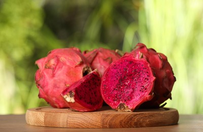 Photo of Delicious cut and whole dragon fruits (pitahaya) on wooden table