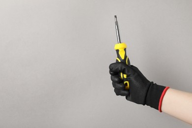 Photo of Woman holding screwdriver on grey background, closeup. Space for text