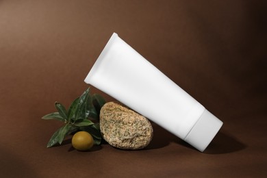 Tube of natural cream, stone and olive on brown background. Cosmetic products