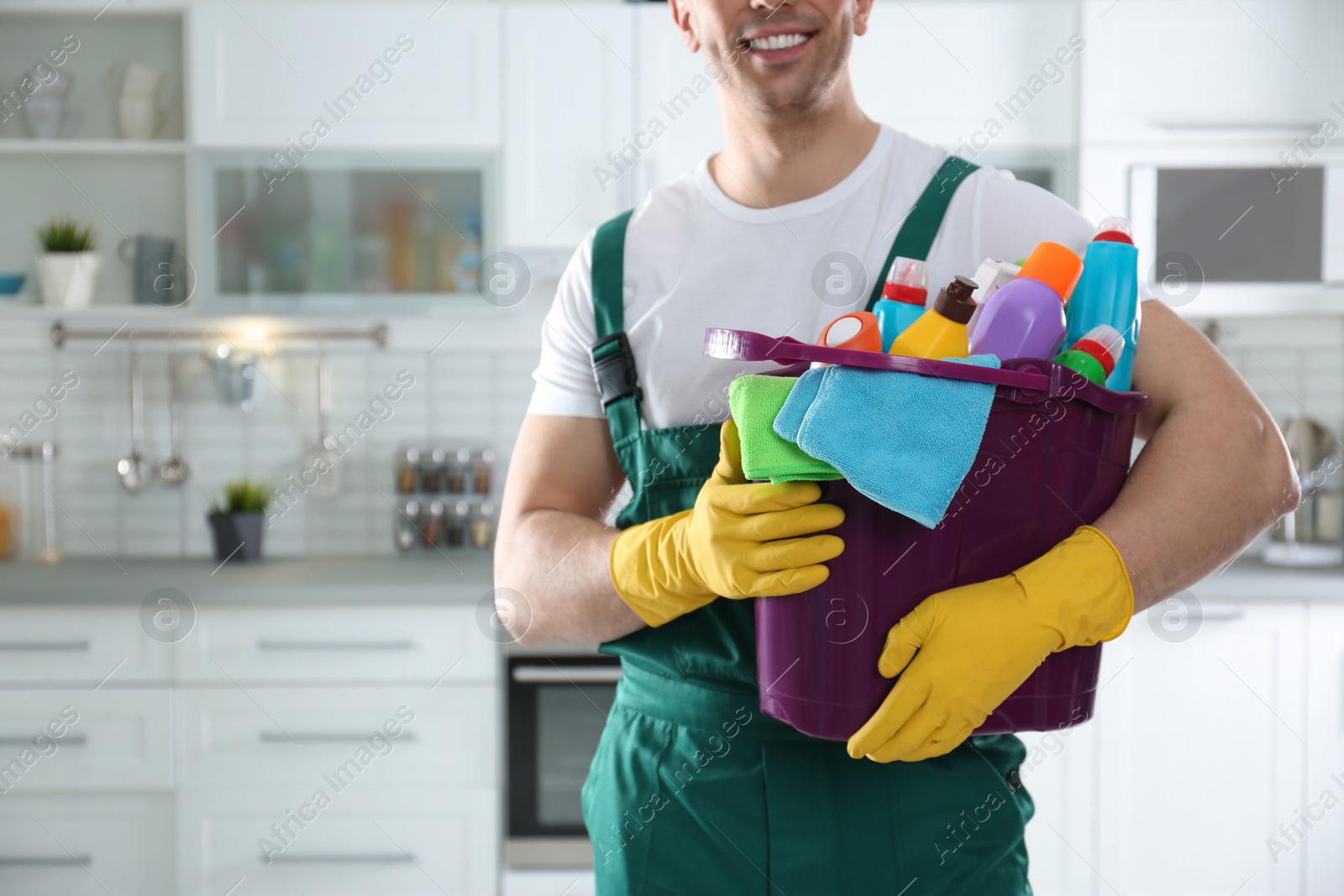 Photo of Janitor with bucket of detergents in kitchen, closeup. Cleaning service