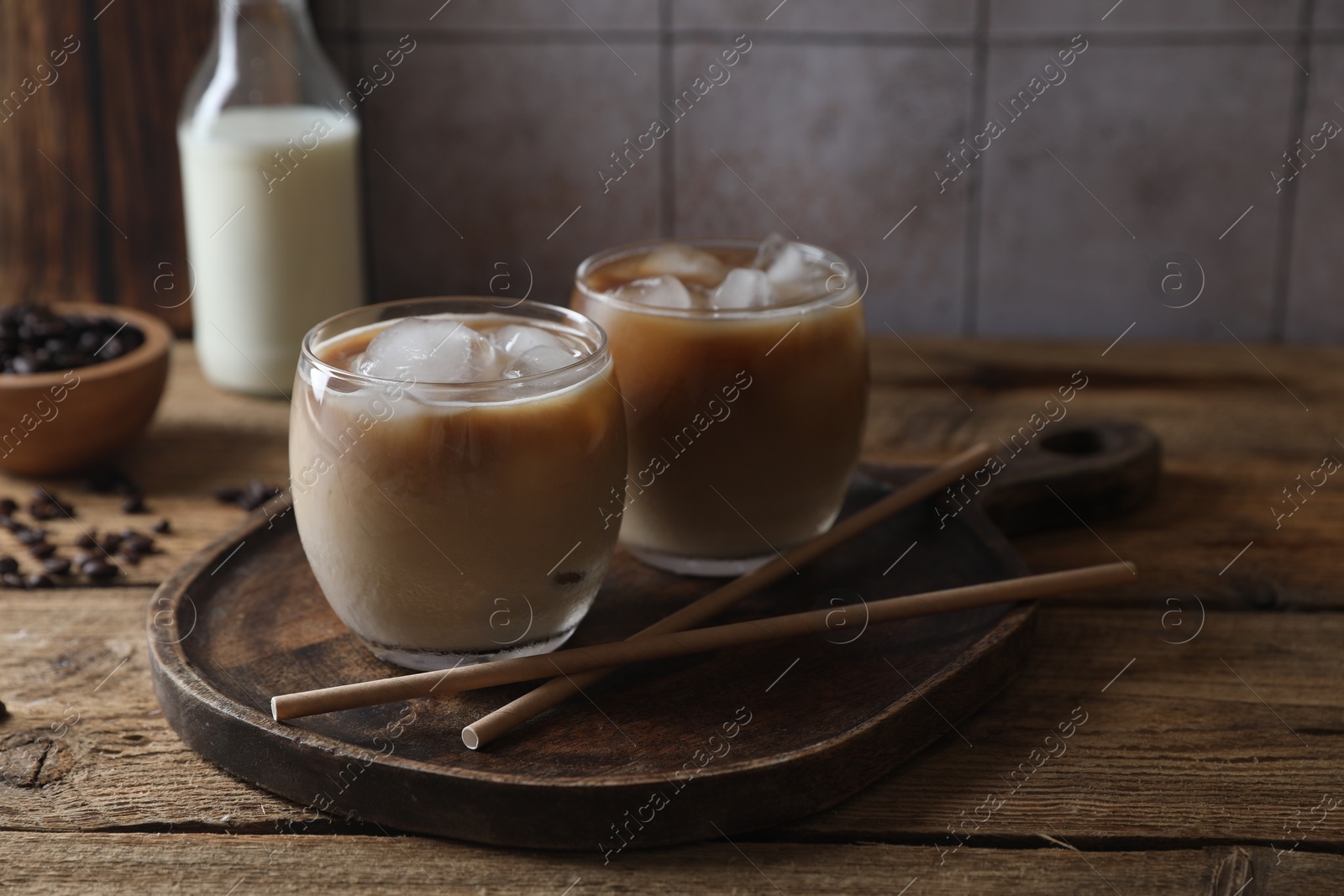 Photo of Refreshing iced coffee with milk in glasses and straws on wooden table