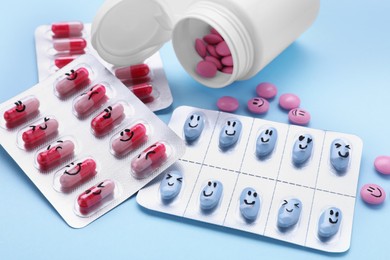 Blister, bottle and antidepressant pills with funny faces on light blue background