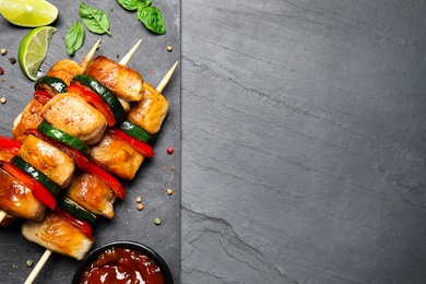 Delicious chicken shish kebabs with vegetables on black table, flat lay. Space for text