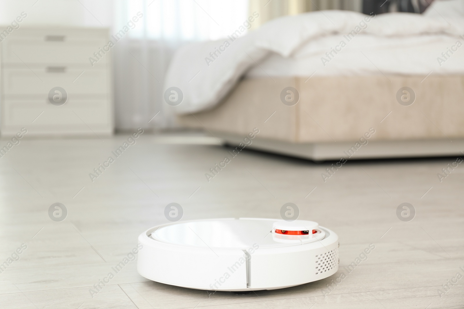 Photo of Modern robotic vacuum cleaner on floor in bedroom. Space for text