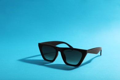 Stylish sunglasses on light blue background. Space for text