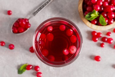 Tasty cranberry juice in glass and fresh berries on light grey table, top view