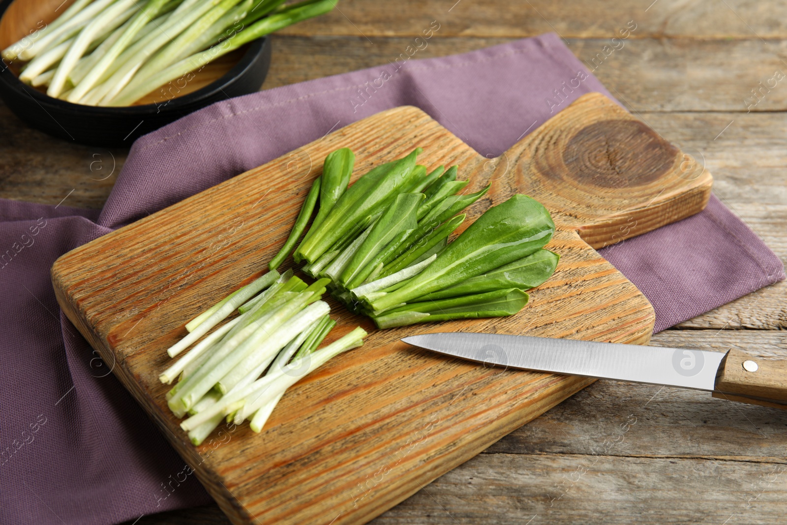 Photo of Board with wild garlic or ramson on wooden table