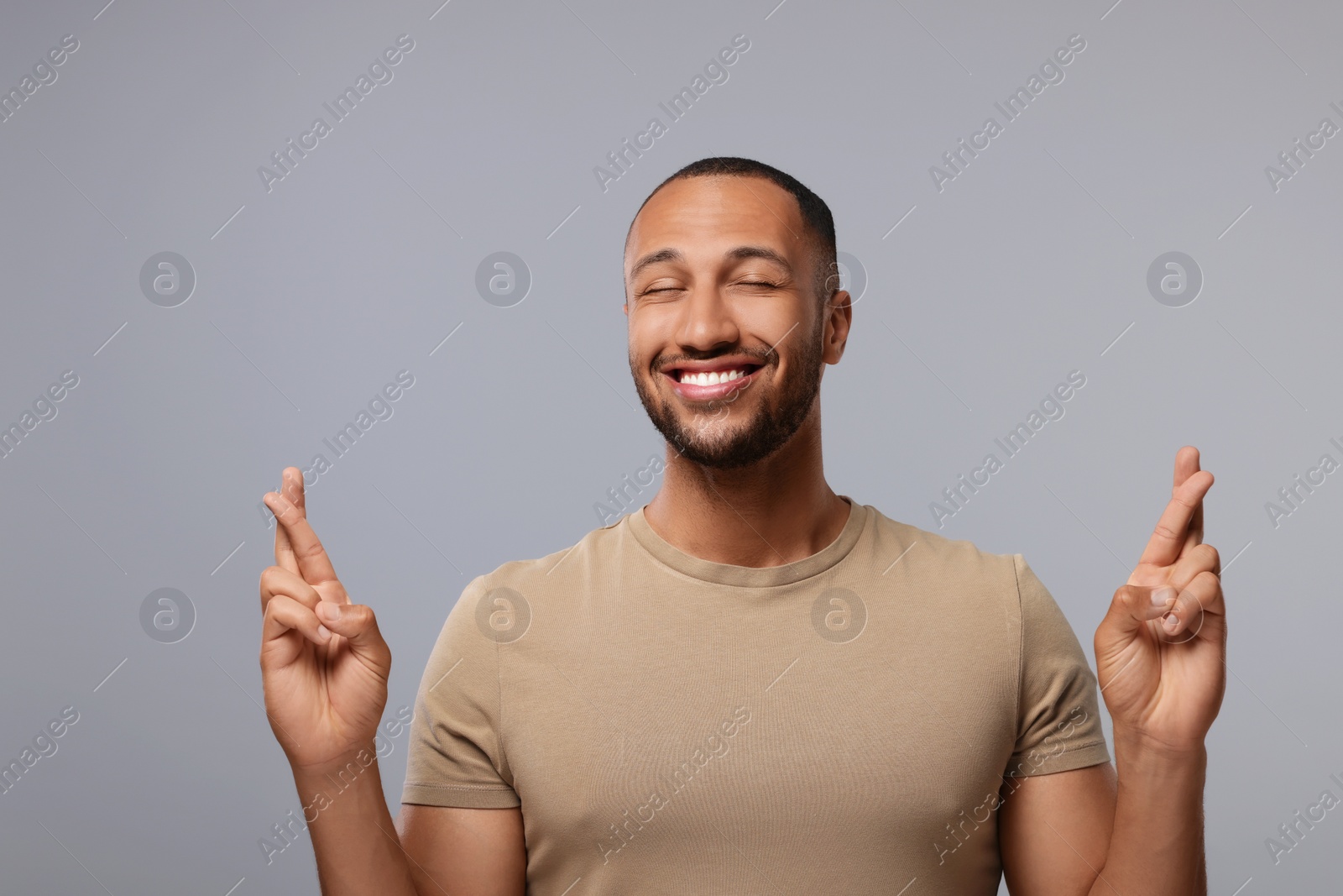 Photo of Happy man crossing his fingers on grey background