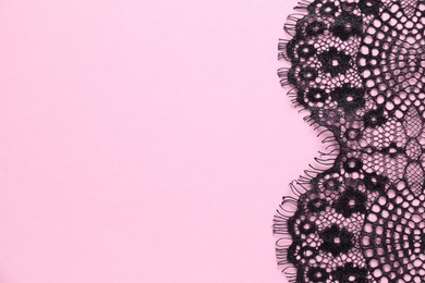 Photo of Black lace on pink background, top view. Space for text