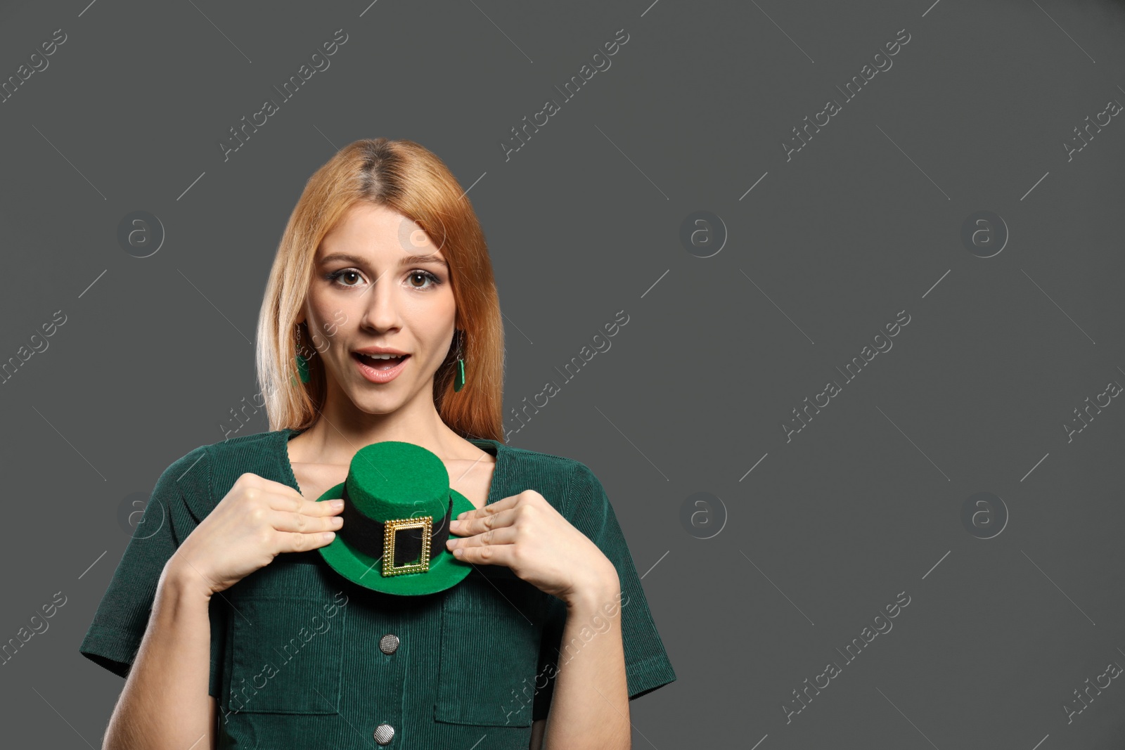 Photo of Young woman with green leprechaun hat on grey background, space for text. St. Patrick's Day celebration