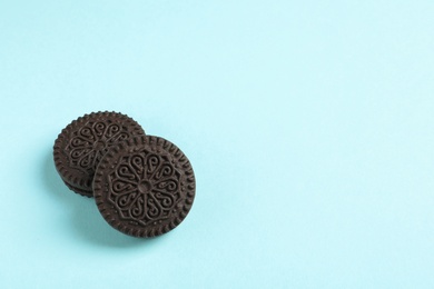 Photo of Tasty chocolate cookies with cream on color background, top view. Space for text