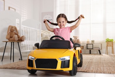 Adorable child driving toy car in room at home