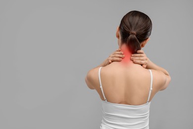 Image of Woman suffering from neck pain on grey background, back view