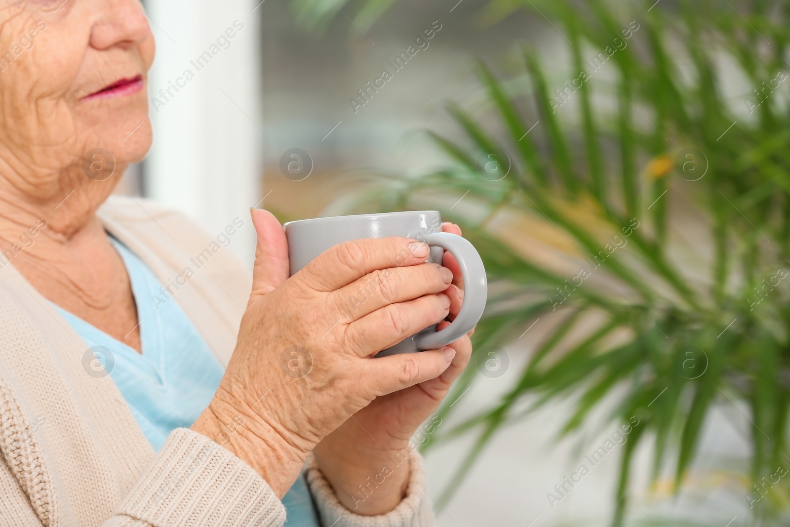 Photo of Closeup view of elderly woman with cup of tea in nursing home, space for text. Assisting senior generation