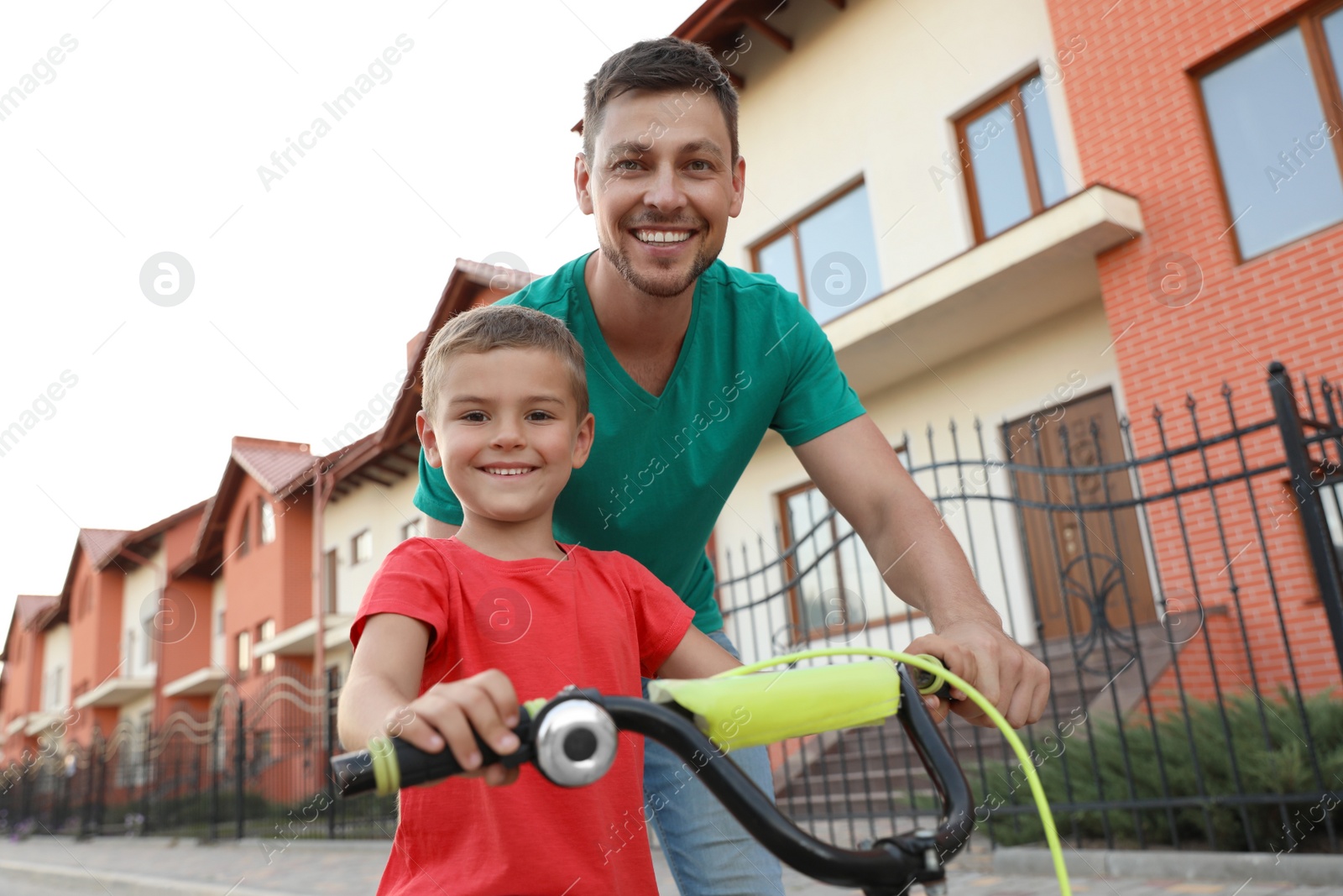 Photo of Happy father teaching his son to ride bicycle on street