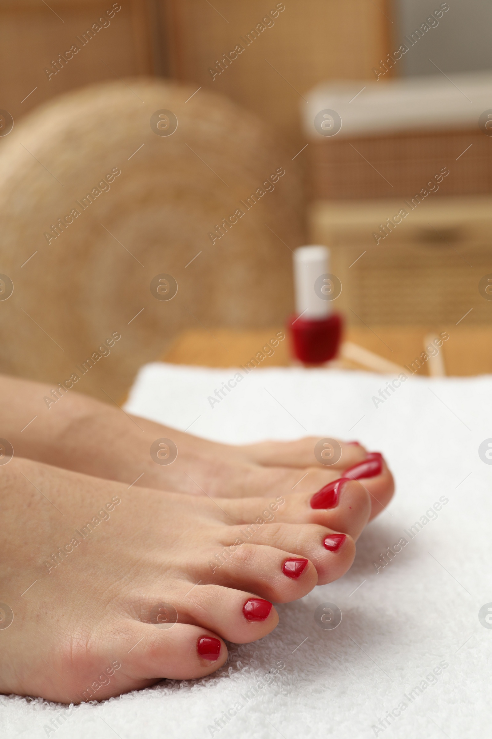 Photo of Woman with stylish red toenails after pedicure procedure on white terry towel indoors, closeup