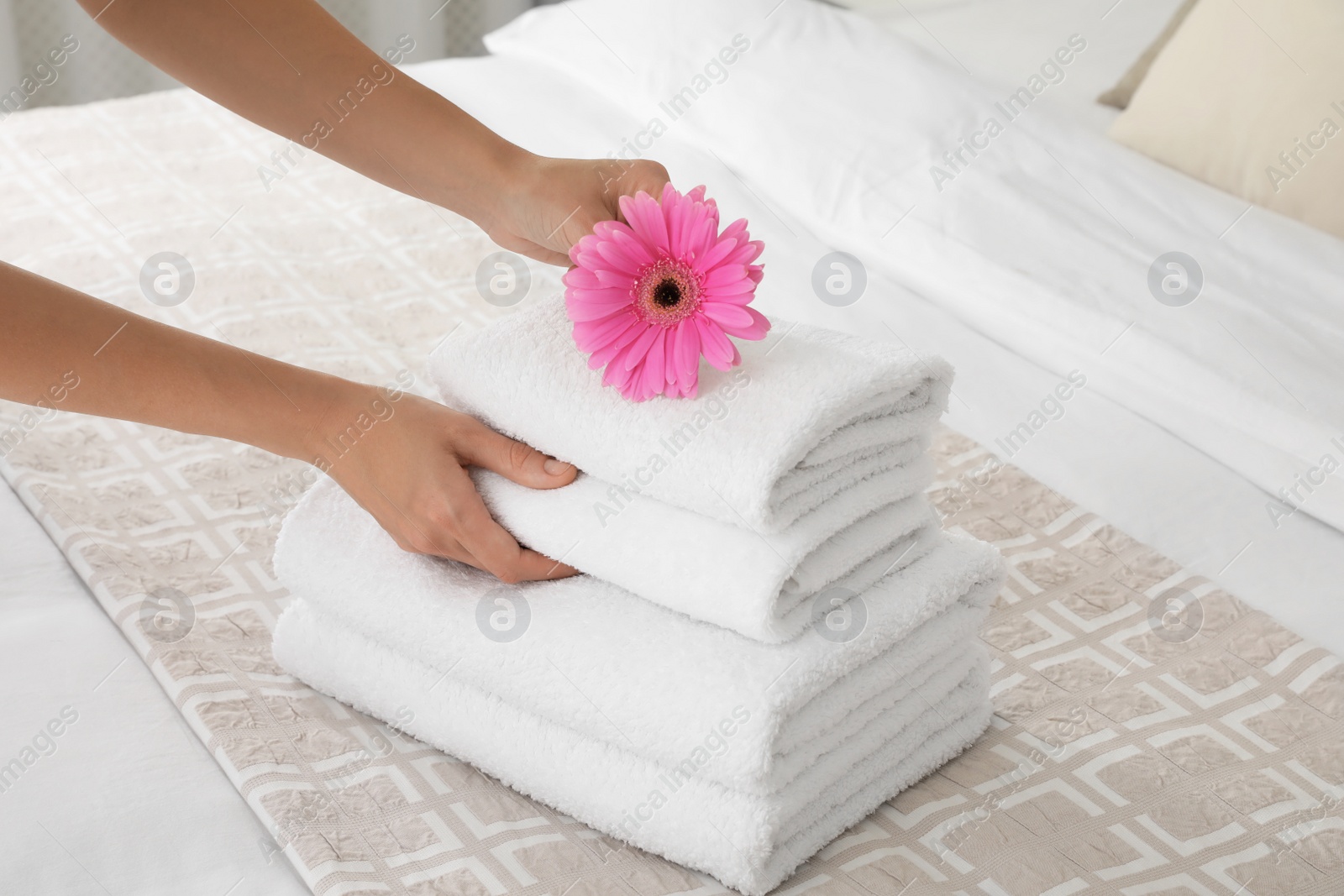 Photo of Woman putting flower on fresh towels in room, closeup