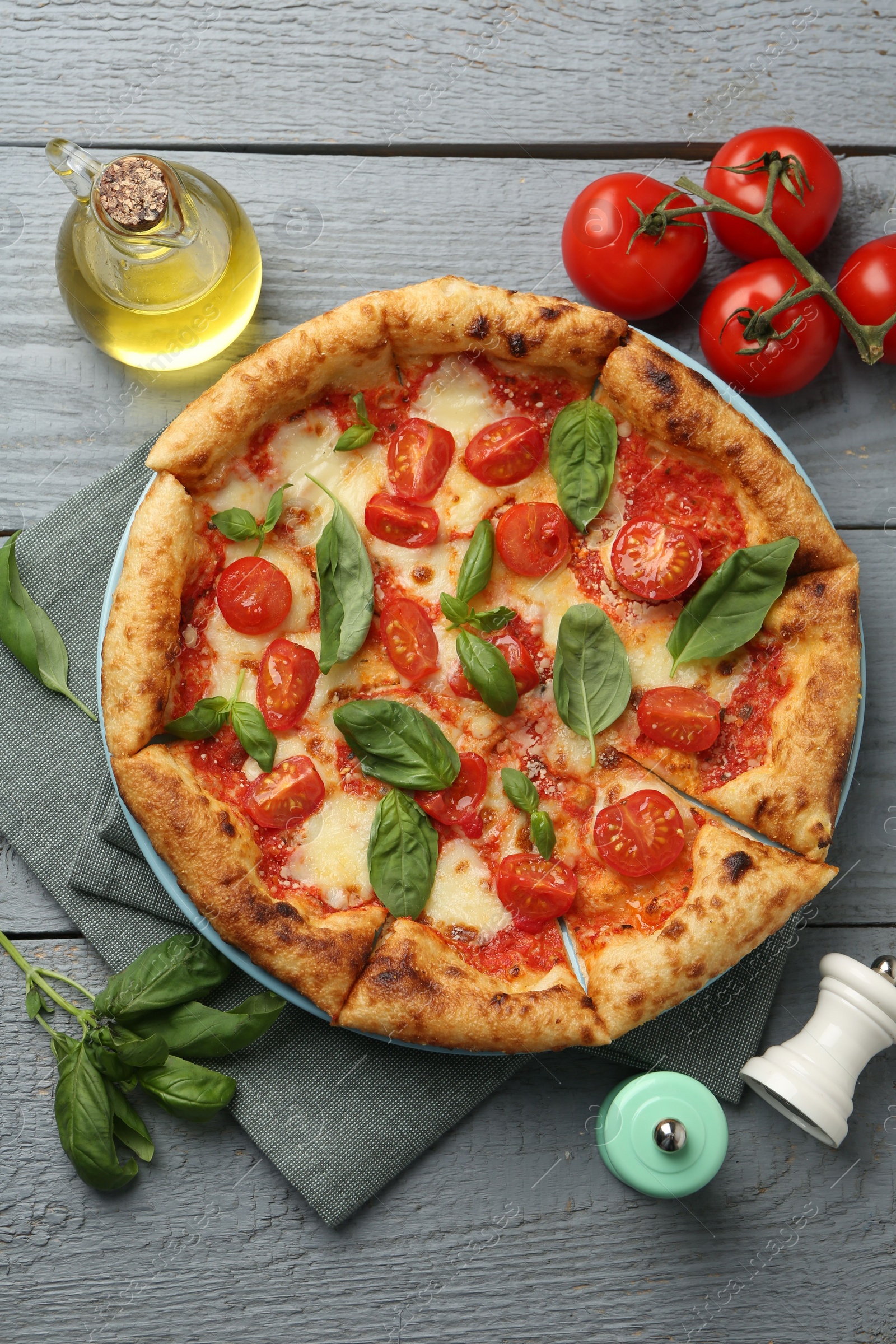 Photo of Delicious Margherita pizza and ingredients on gray wooden table, flat lay