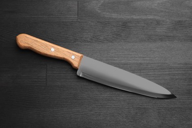 Photo of One sharp knife on black wooden table, top view