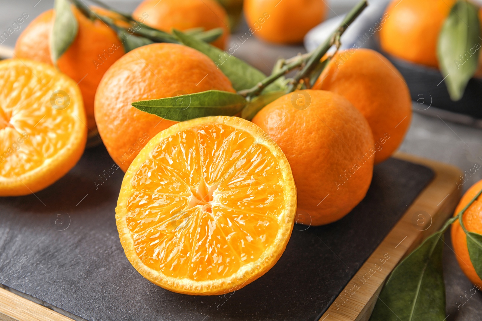 Photo of Board with ripe tangerines on table, closeup. Citrus fruit