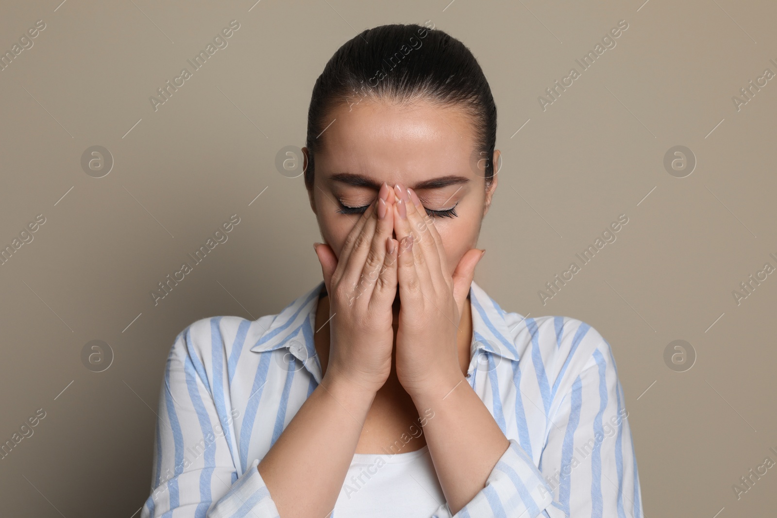 Photo of Young woman suffering from headache on beige background