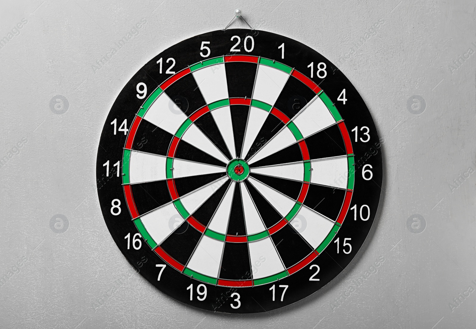 Photo of Dart board hanging on grey concrete wall