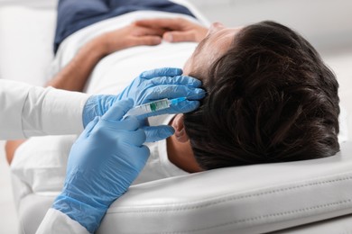 Trichologist giving injection to patient in clinic, closeup