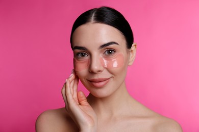 Photo of Beautiful young woman with under eye patches on pink background