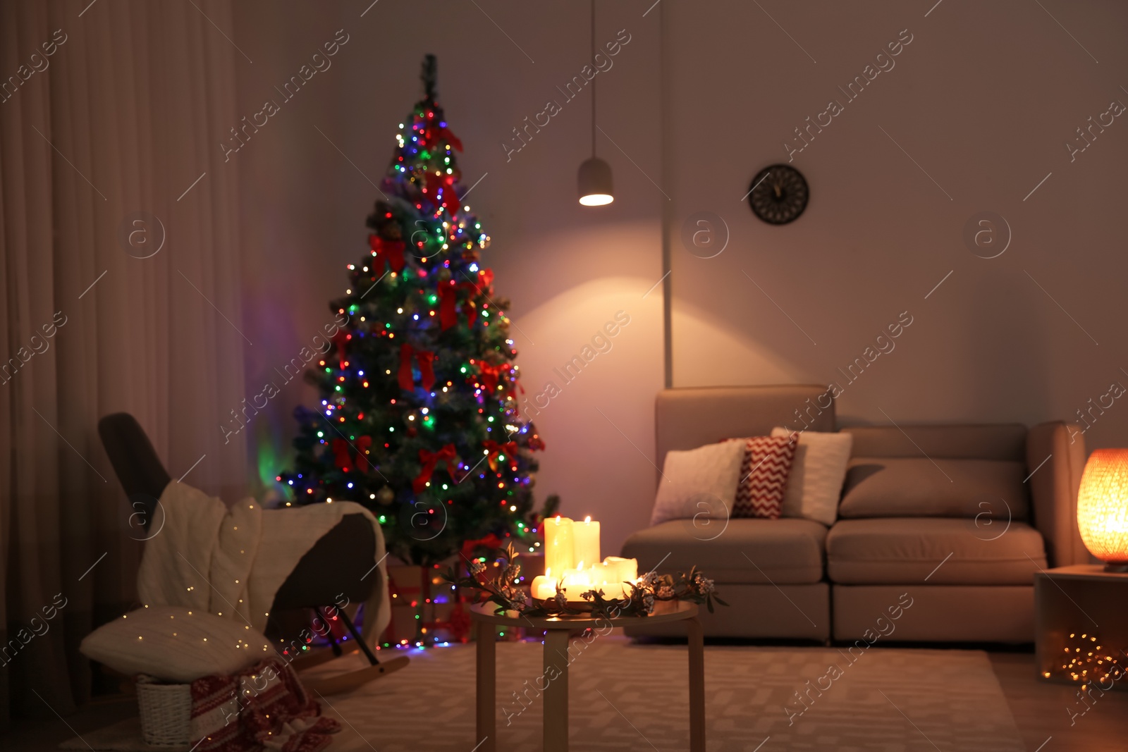 Photo of Stylish room interior with candles and decorated Christmas tree