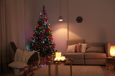 Photo of Stylish room interior with candles and decorated Christmas tree