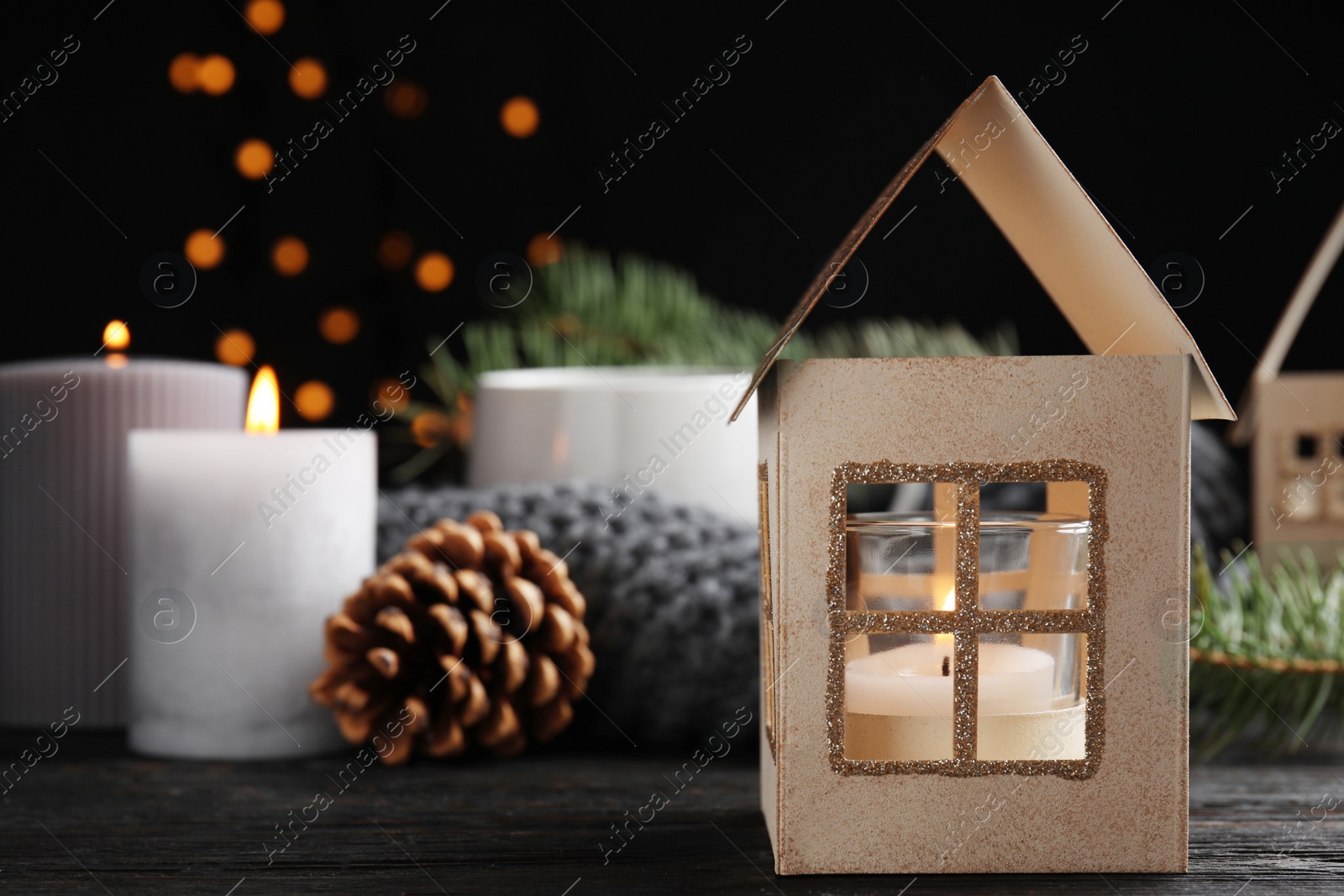 Photo of Composition with candle in house shaped holder on wooden table. Christmas decoration