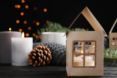 Photo of Composition with candle in house shaped holder on wooden table. Christmas decoration