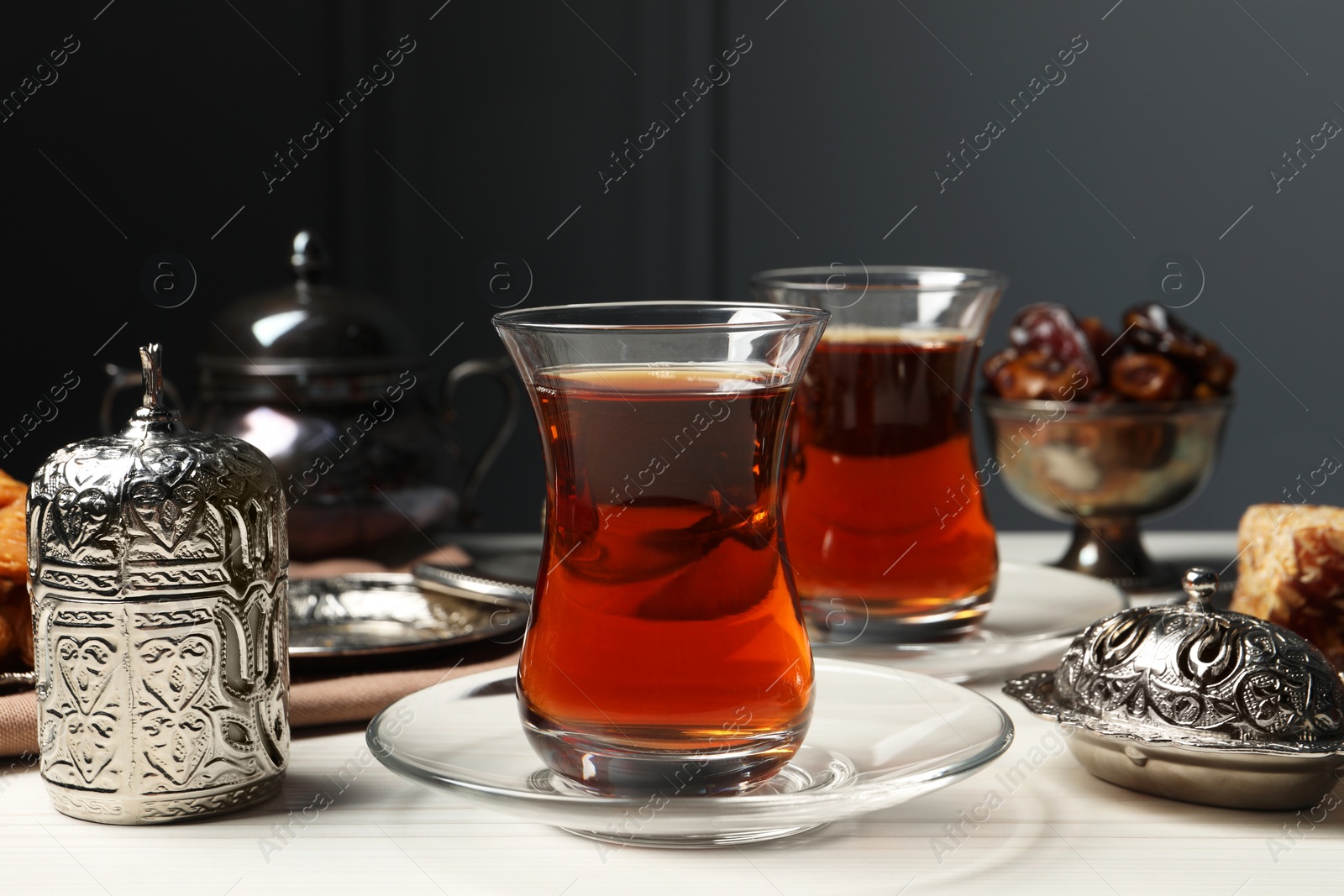 Photo of Glasses of tea and vintage tea set on white wooden table