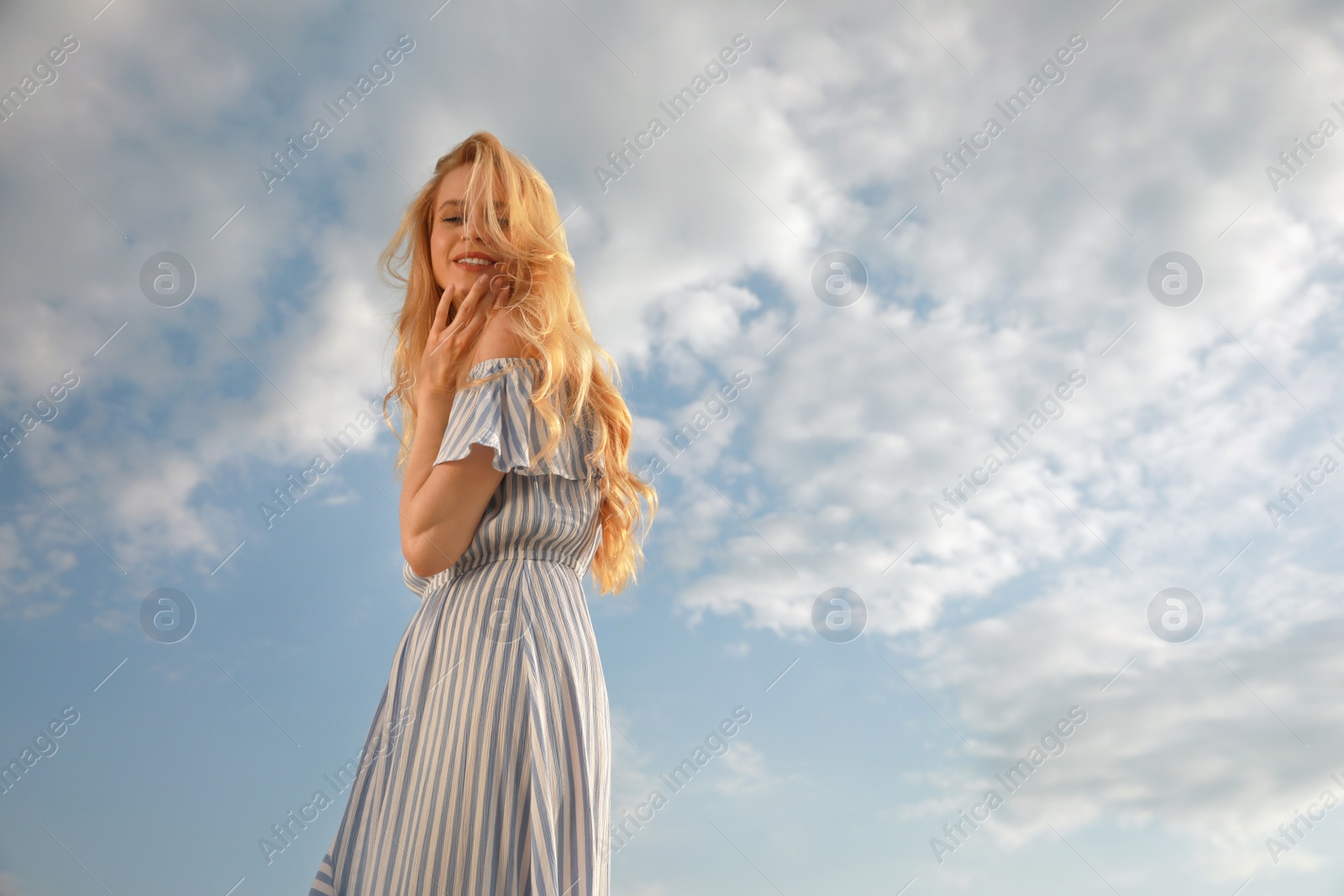 Photo of Beautiful young woman against blue sky on sunny day, space for text