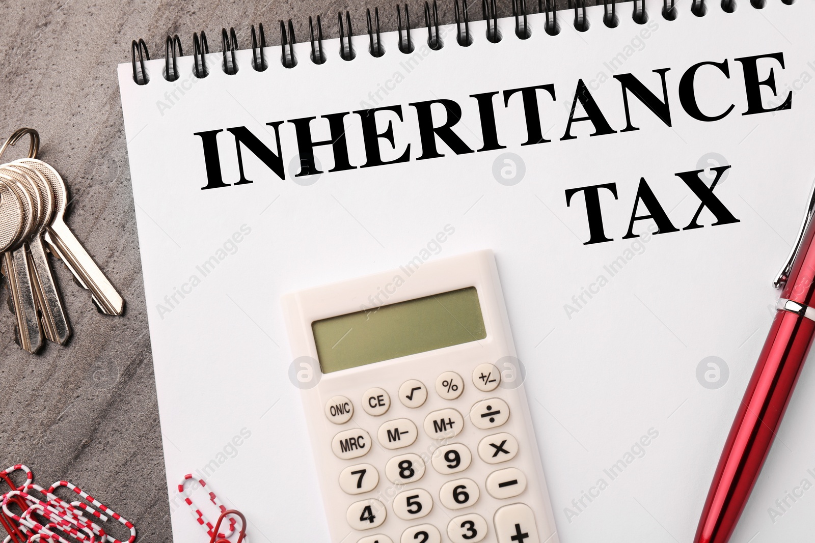 Photo of Inheritance Tax. Notebook, keys and office stationery on grey table, flat lay