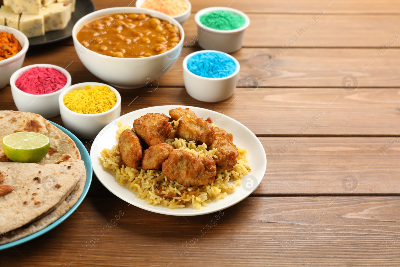 Photo of Traditional Indian food and color powders on wooden table. Holi festival celebration