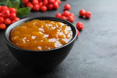 Photo of Delicious rowan jam in bowl on dark table, closeup. Space for text