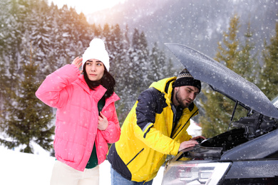 Photo of Stressed couple near broken car outdoors on winter day
