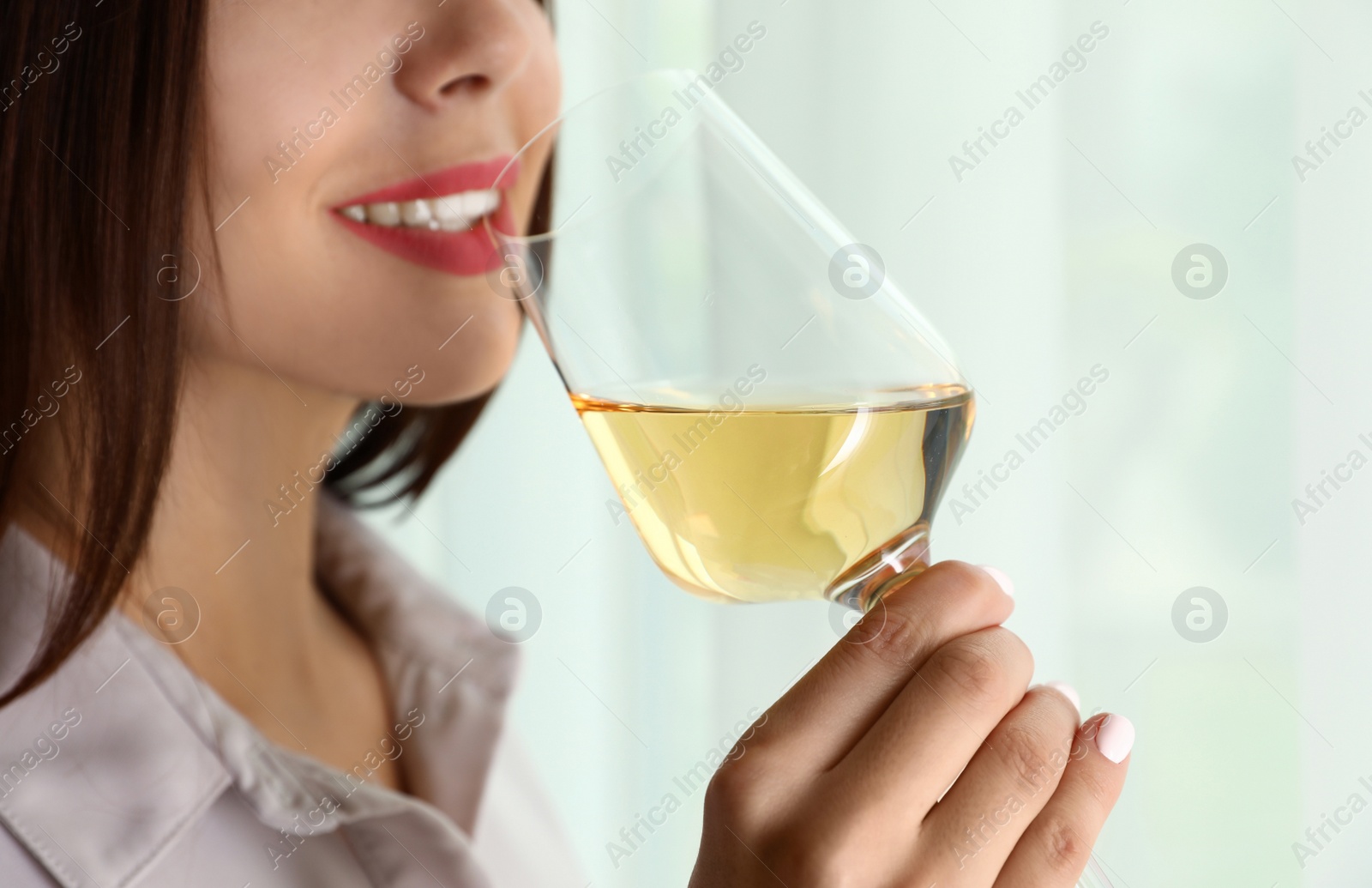 Photo of Young woman with glass of luxury white wine indoors, closeup. Space for text