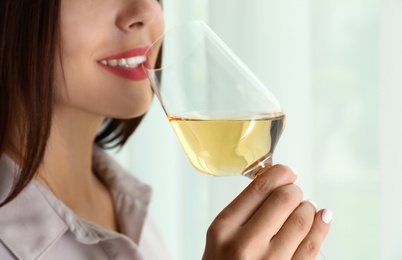 Photo of Young woman with glass of luxury white wine indoors, closeup. Space for text