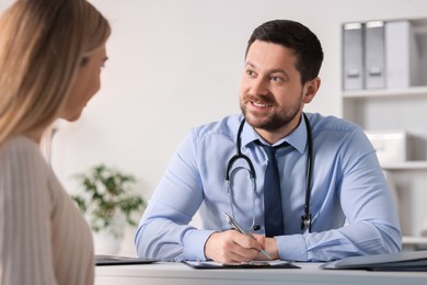 Photo of Professional doctor working with patient at white table in hospital