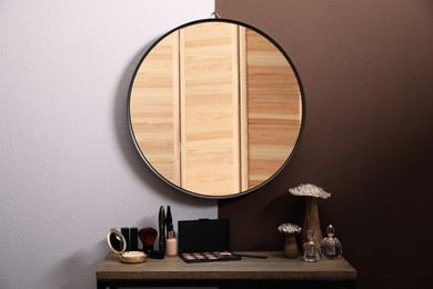 Photo of Stylish dressing table with cosmetics, mirror and accessories near color wall