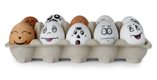 Photo of Eggs with different drawn faces in cardboard package on white background