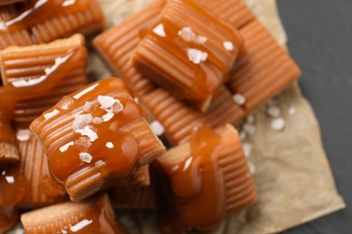 Tasty caramel candies with sauce and sea salt on grey table, closeup