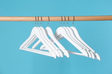 Wooden rack with clothes hangers on color background