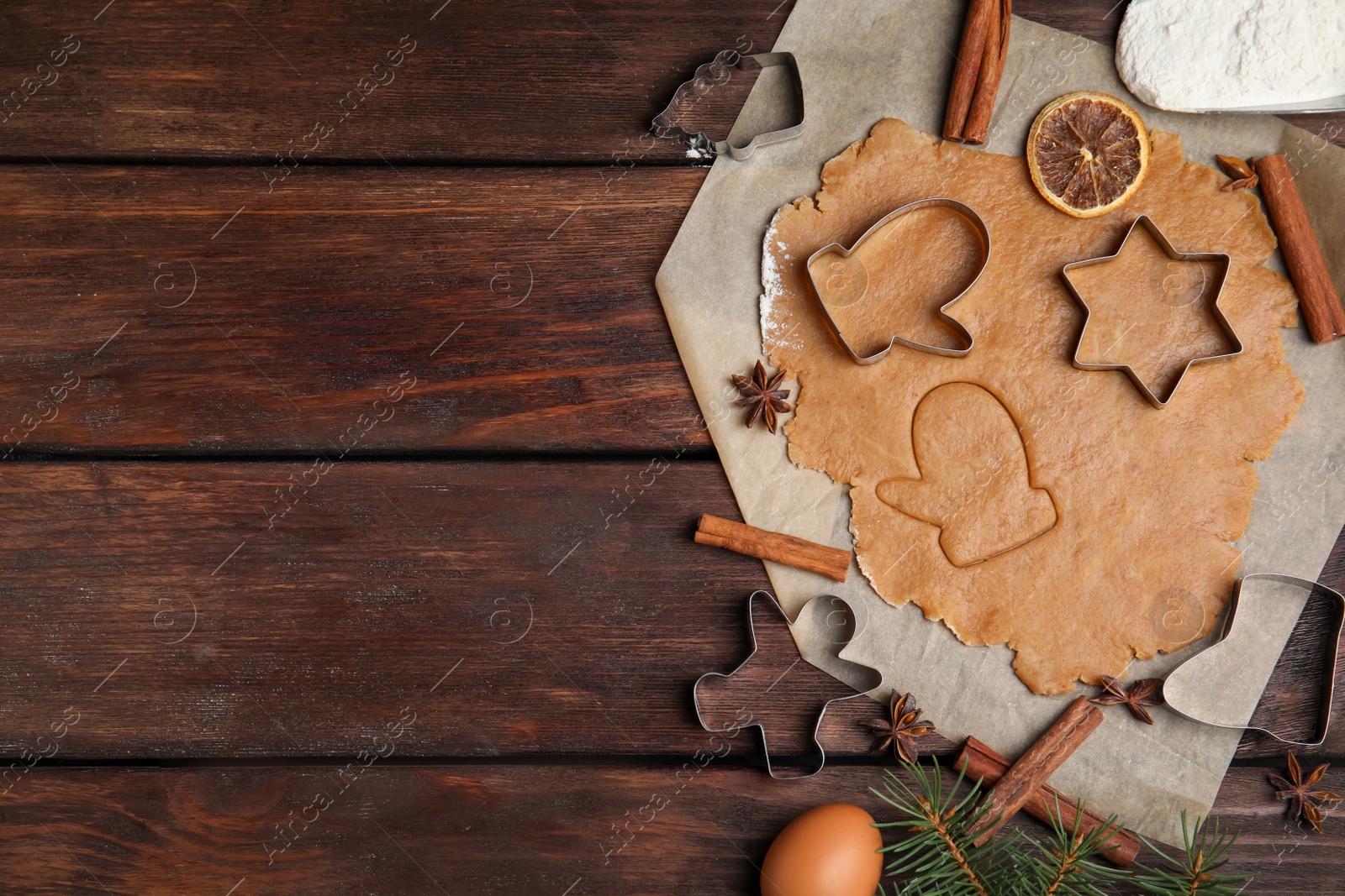 Photo of Dough, different cutters and ingredients for Christmas cookies on wooden table, flat lay. Space for text